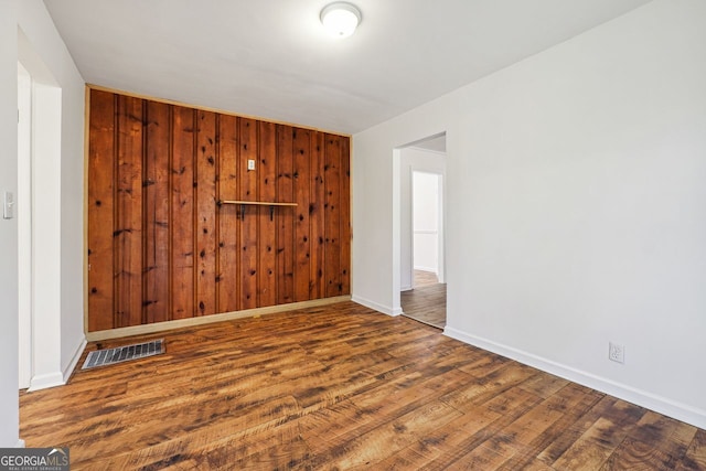 spare room with wooden walls and wood-type flooring