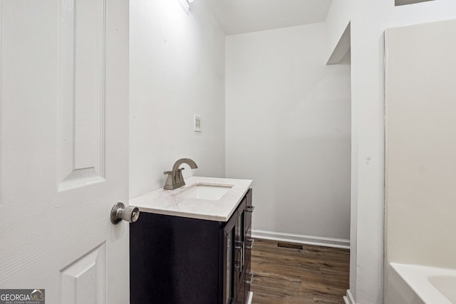 bathroom with vanity, wood-type flooring, and a tub to relax in