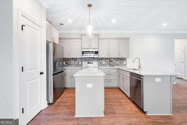 kitchen featuring light stone counters, stainless steel appliances, a kitchen island, and sink