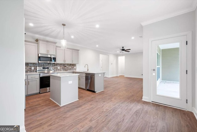 kitchen with gray cabinetry, a center island, decorative light fixtures, light hardwood / wood-style floors, and stainless steel appliances