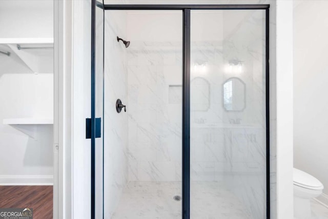 bathroom with hardwood / wood-style flooring, toilet, and a shower with door