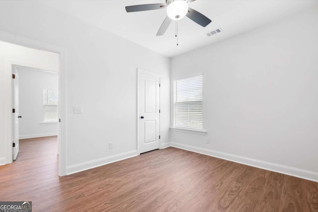 unfurnished bedroom featuring multiple windows, ceiling fan, and wood-type flooring