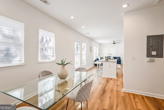 dining room featuring electric panel, ceiling fan, a healthy amount of sunlight, and light wood-type flooring