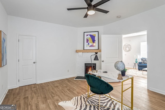 home office featuring hardwood / wood-style floors, a brick fireplace, and ceiling fan