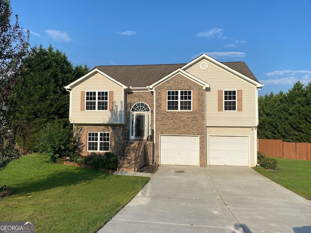 raised ranch featuring a garage and a front lawn