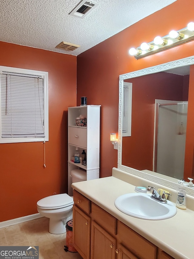 bathroom with vanity, a shower with shower door, toilet, and a textured ceiling