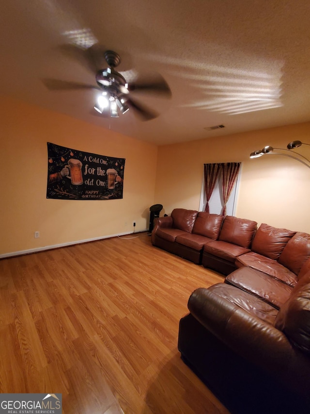 living room with hardwood / wood-style floors, a textured ceiling, and ceiling fan