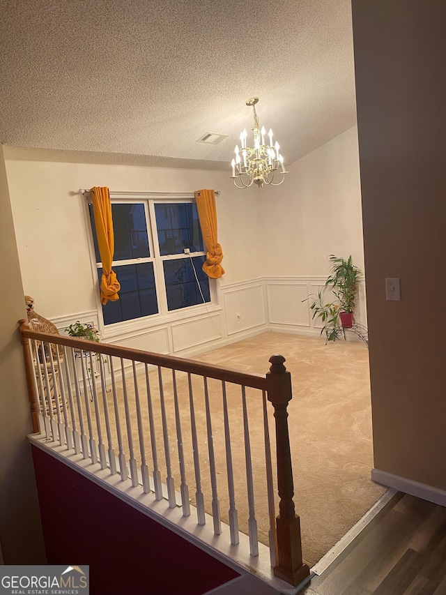 stairway featuring a notable chandelier and a textured ceiling