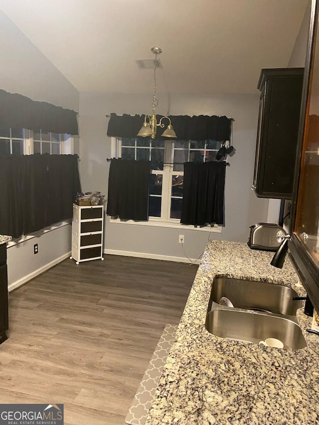 kitchen with dark hardwood / wood-style flooring, sink, light stone counters, and hanging light fixtures