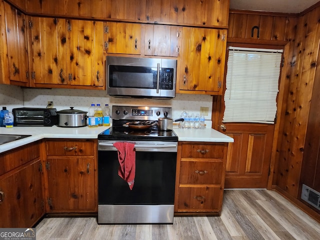 kitchen with tasteful backsplash, stainless steel appliances, and light wood-type flooring