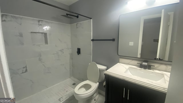 bathroom featuring tiled shower, vanity, and toilet