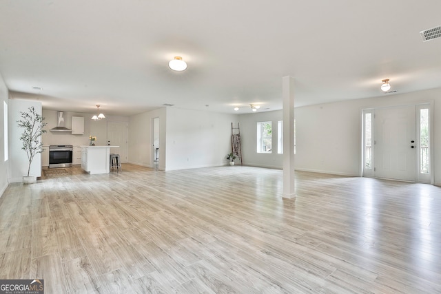 unfurnished living room featuring light wood-type flooring and a chandelier