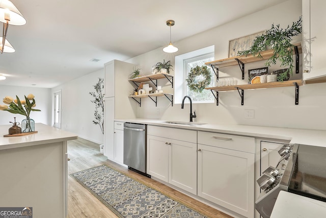 kitchen featuring sink, stainless steel dishwasher, light wood-type flooring, decorative light fixtures, and white cabinetry