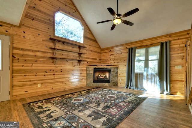 living room with hardwood / wood-style floors, ceiling fan, high vaulted ceiling, and wooden walls