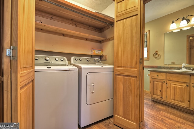 laundry area featuring washing machine and dryer, dark hardwood / wood-style flooring, and sink