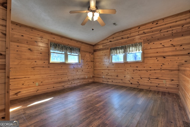 empty room with plenty of natural light, dark hardwood / wood-style flooring, and wooden walls