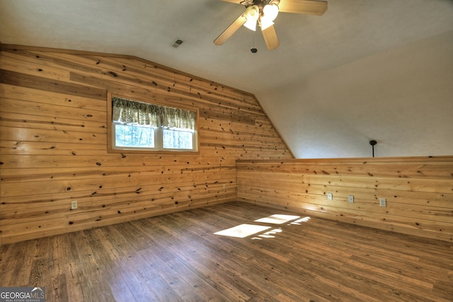 additional living space featuring wood-type flooring, wooden walls, ceiling fan, and lofted ceiling