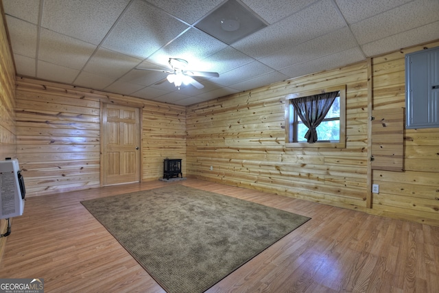 unfurnished room featuring hardwood / wood-style flooring, a drop ceiling, wood walls, and ceiling fan