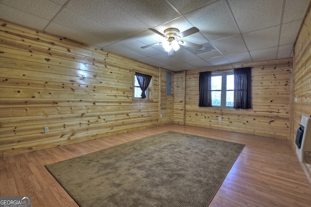 interior space featuring a paneled ceiling, wood walls, and hardwood / wood-style floors