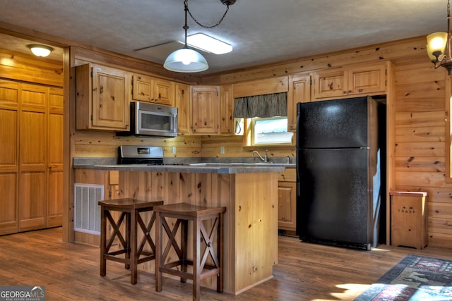 kitchen featuring wooden walls, dark hardwood / wood-style floors, a kitchen bar, and appliances with stainless steel finishes