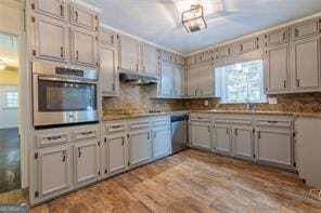 kitchen with stainless steel appliances, sink, light hardwood / wood-style floors, and decorative backsplash