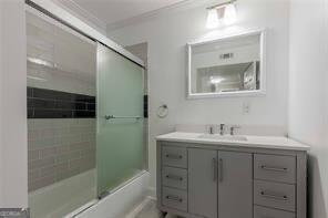 bathroom with crown molding, vanity, and shower / bath combination with glass door