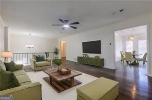 living room with ceiling fan with notable chandelier and dark hardwood / wood-style flooring