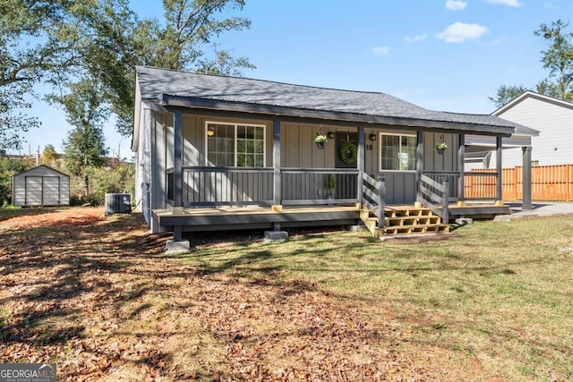 view of front of home with a front yard, a porch, cooling unit, and a storage shed