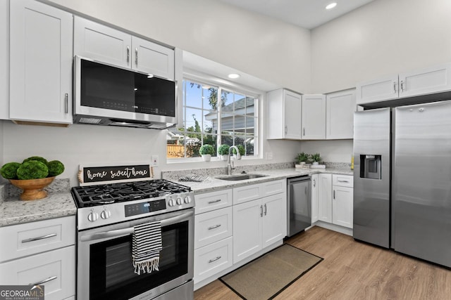 18 Watson Dr, Newnan, GA 30263 - kitchen with appliances with stainless steel finishes, a sink, white cabinets, light wood-style flooring, and light stone countertops