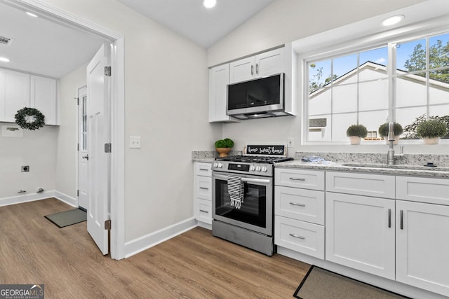 18 Watson Dr, Newnan, GA 30263 - kitchen with stainless steel range with gas stovetop, a sink, light wood-style flooring, white cabinetry, and recessed lighting