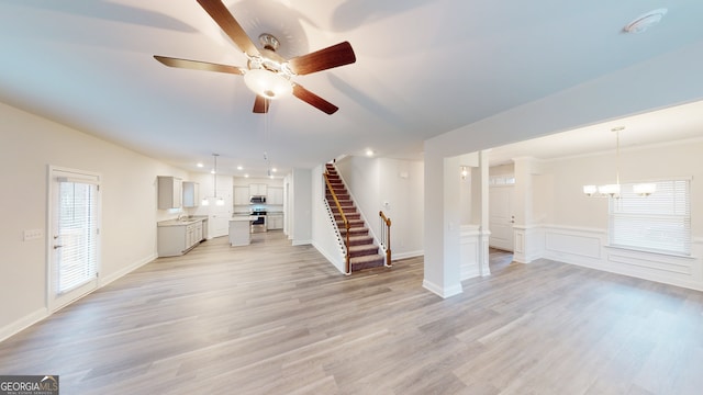 unfurnished living room with light hardwood / wood-style floors and ceiling fan with notable chandelier