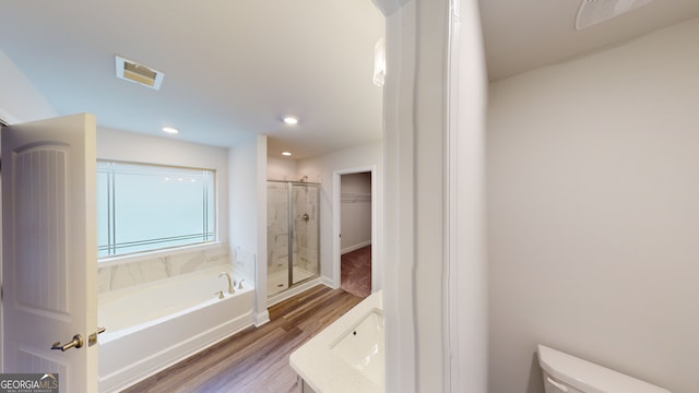 full bathroom with hardwood / wood-style floors, vanity, separate shower and tub, and toilet