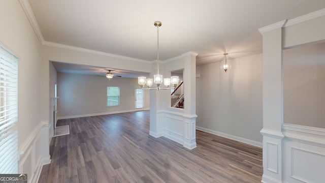 unfurnished dining area with dark hardwood / wood-style floors, ornamental molding, and ceiling fan with notable chandelier