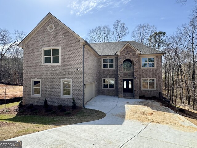 traditional home featuring a garage, concrete driveway, and brick siding