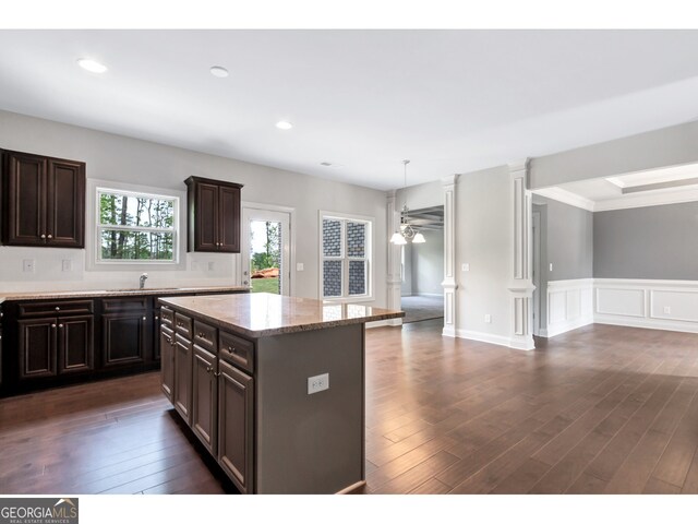 kitchen featuring dark hardwood / wood-style flooring, dark brown cabinetry, ceiling fan, pendant lighting, and a kitchen island