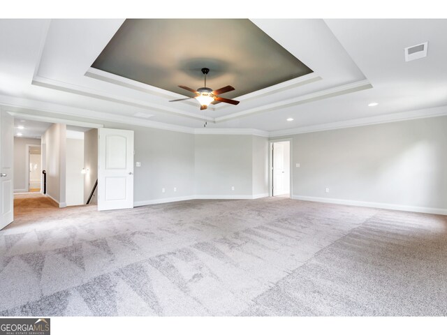 unfurnished room with light carpet, a tray ceiling, ceiling fan, and crown molding