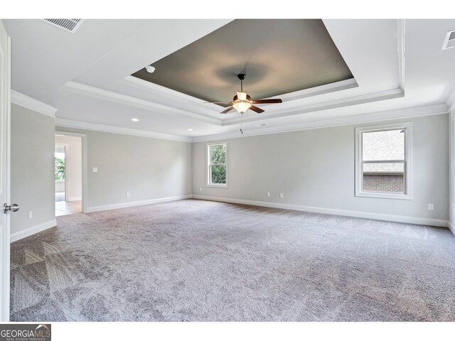 unfurnished room featuring a raised ceiling, crown molding, carpet flooring, and ceiling fan