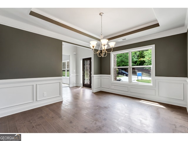 spare room with a tray ceiling, crown molding, a healthy amount of sunlight, and a notable chandelier