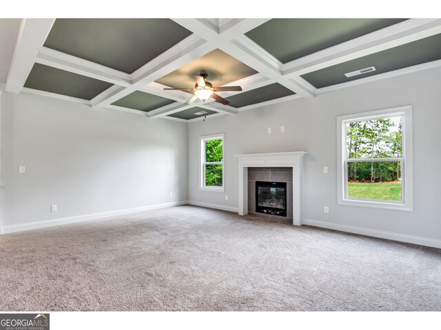 unfurnished living room featuring ceiling fan, coffered ceiling, beamed ceiling, carpet floors, and a tiled fireplace