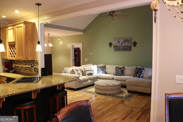 living room featuring ceiling fan, sink, ornamental molding, and light wood-type flooring