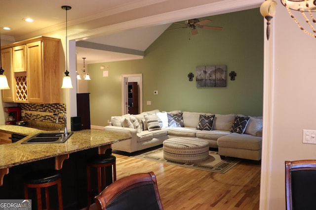 living room featuring light hardwood / wood-style flooring, sink, lofted ceiling, ceiling fan with notable chandelier, and crown molding