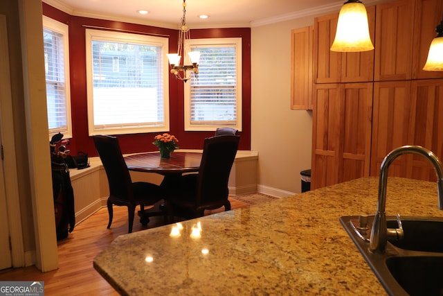 dining area with sink, light hardwood / wood-style floors, a notable chandelier, and ornamental molding