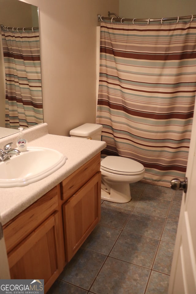 bathroom with tile patterned floors, curtained shower, vanity, and toilet