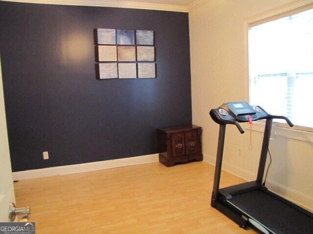 exercise area with ornamental molding and hardwood / wood-style flooring