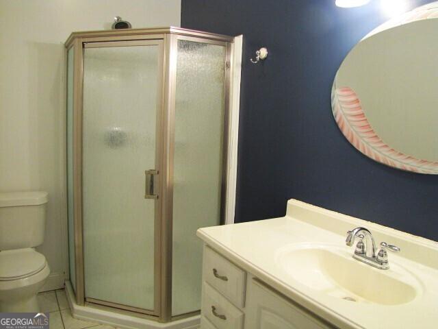 bathroom with toilet, tile patterned flooring, vanity, and walk in shower