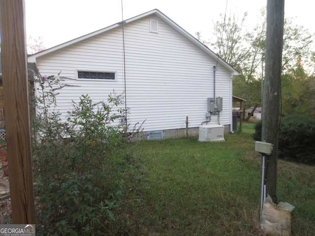 view of side of home with central AC unit and a lawn