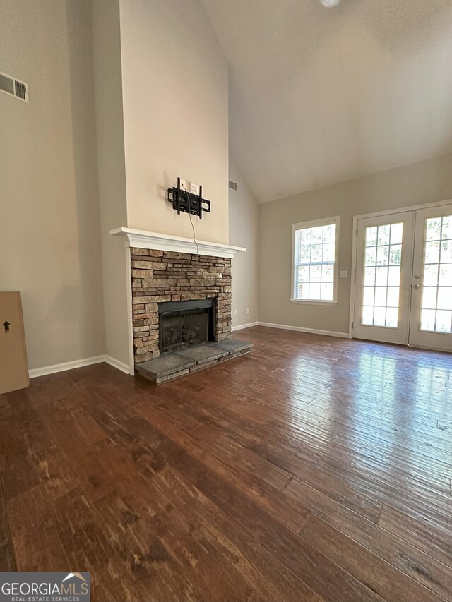 unfurnished living room with a stone fireplace, french doors, high vaulted ceiling, and dark hardwood / wood-style floors