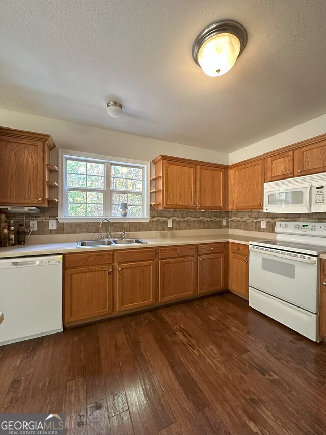 kitchen with sink, tasteful backsplash, dark hardwood / wood-style flooring, a textured ceiling, and white appliances