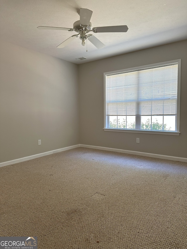 carpeted spare room with a textured ceiling and ceiling fan