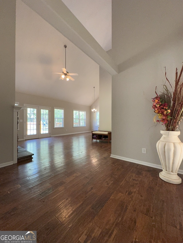 unfurnished living room featuring ceiling fan with notable chandelier, dark wood-type flooring, and high vaulted ceiling